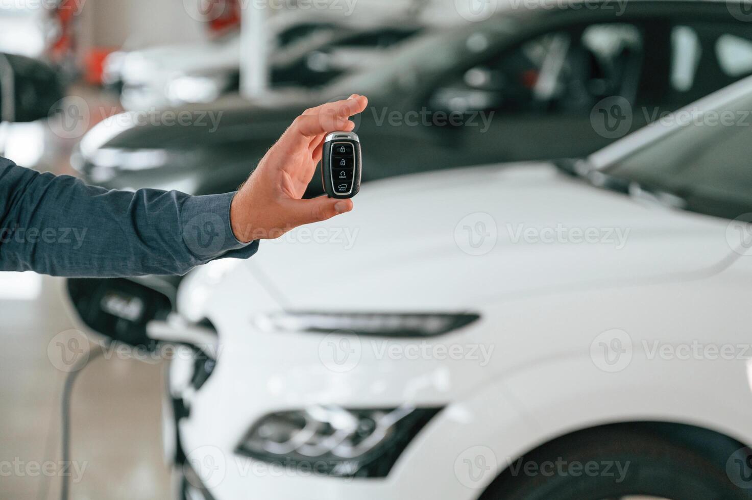 Hand is holding ,the keys. Close up ,view of man that is with electrical car photo