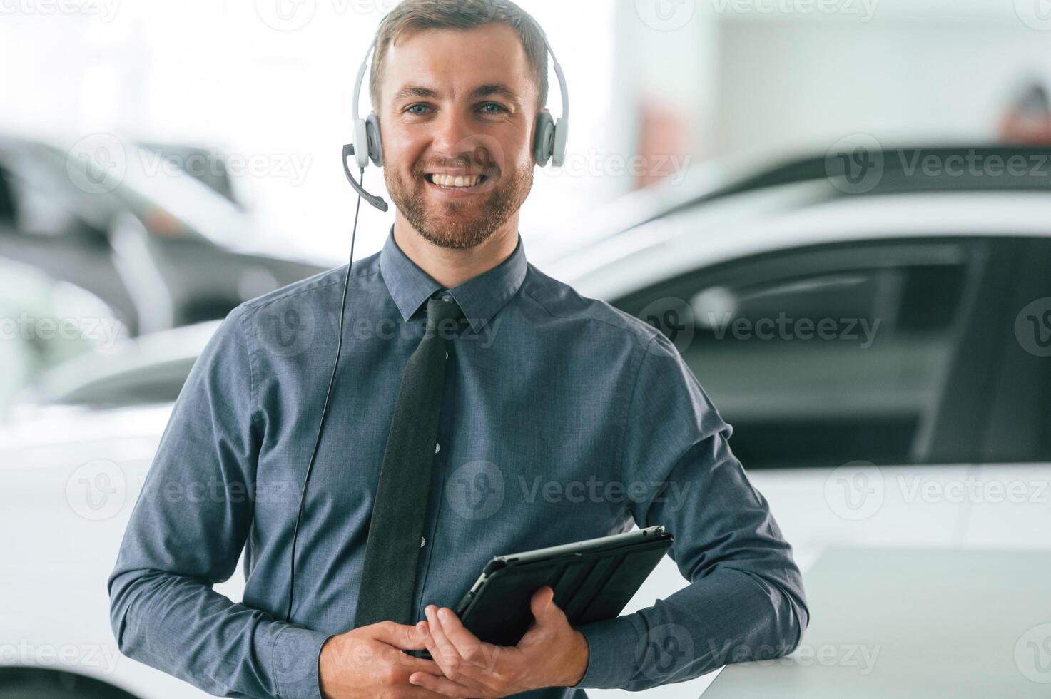 Manager, is, in the headphones and with notepad. Handsome car dealership worker is with electric vehicle photo