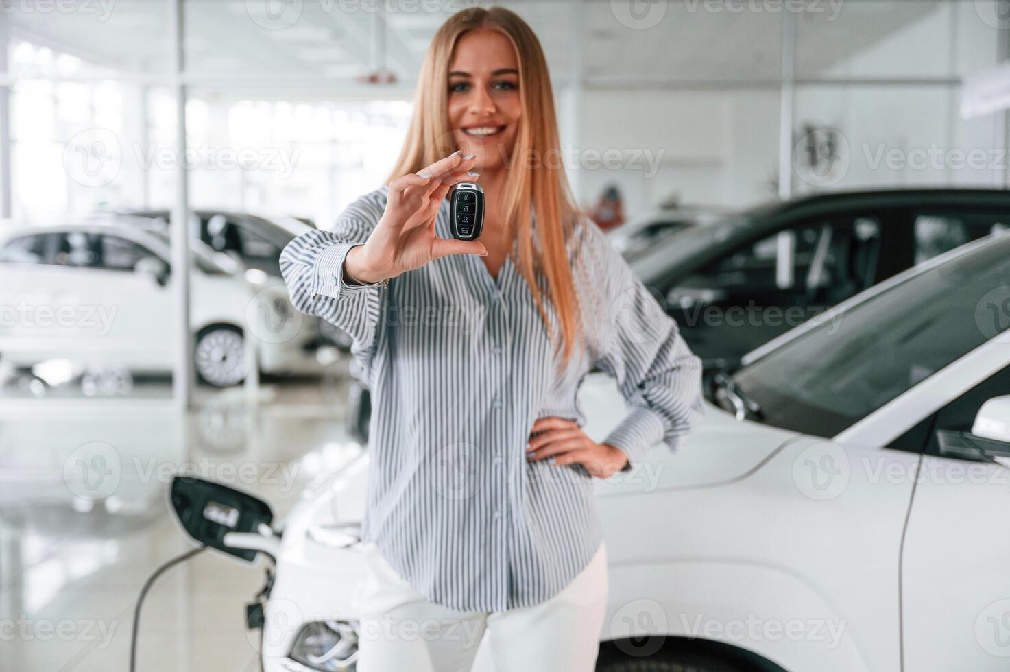 Keys in hands... Beautiful woman is indoors with the modern car photo