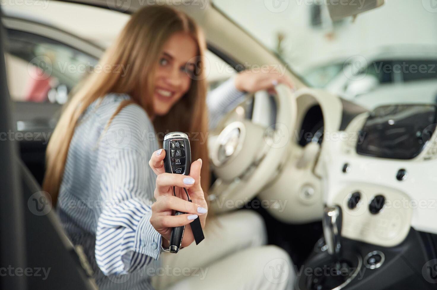 Showing ,the keys ,of new automobile. Beautiful woman is indoors with the modern car photo