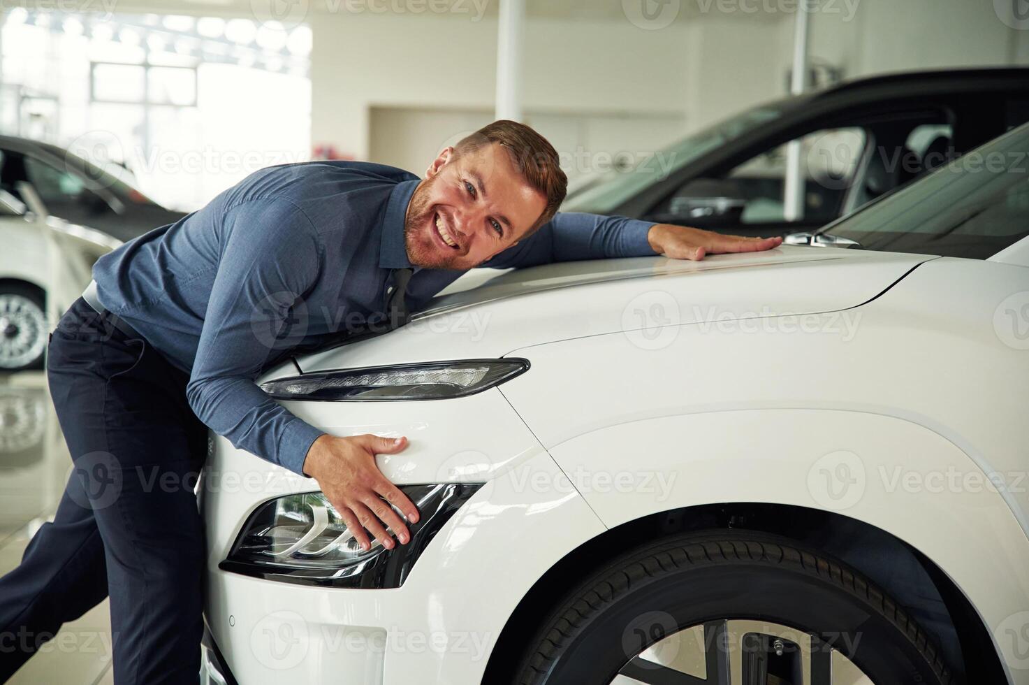 Embracing the new automobile.., Handsome car dealership worker is with electric vehicle photo