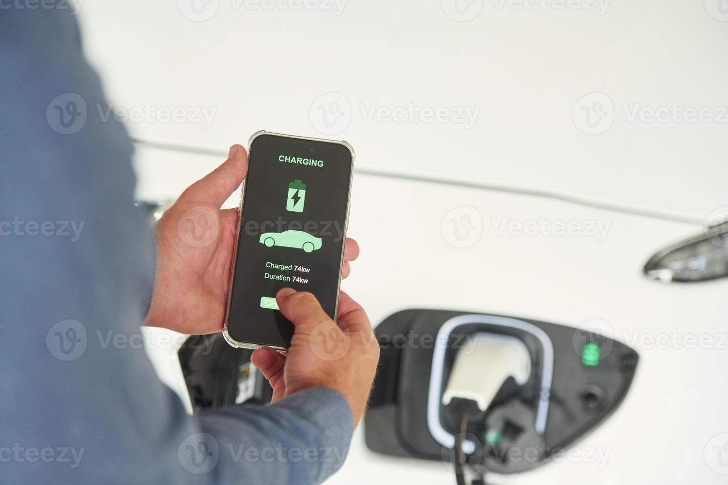 Charging, process on the smartphone app. Close up view of man that is with electrical car photo