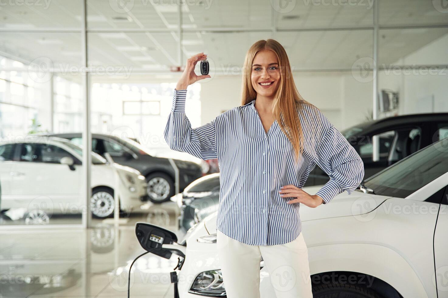 Happy owner of the ,new ,automobile with keys. Beautiful woman is indoors with the modern car photo