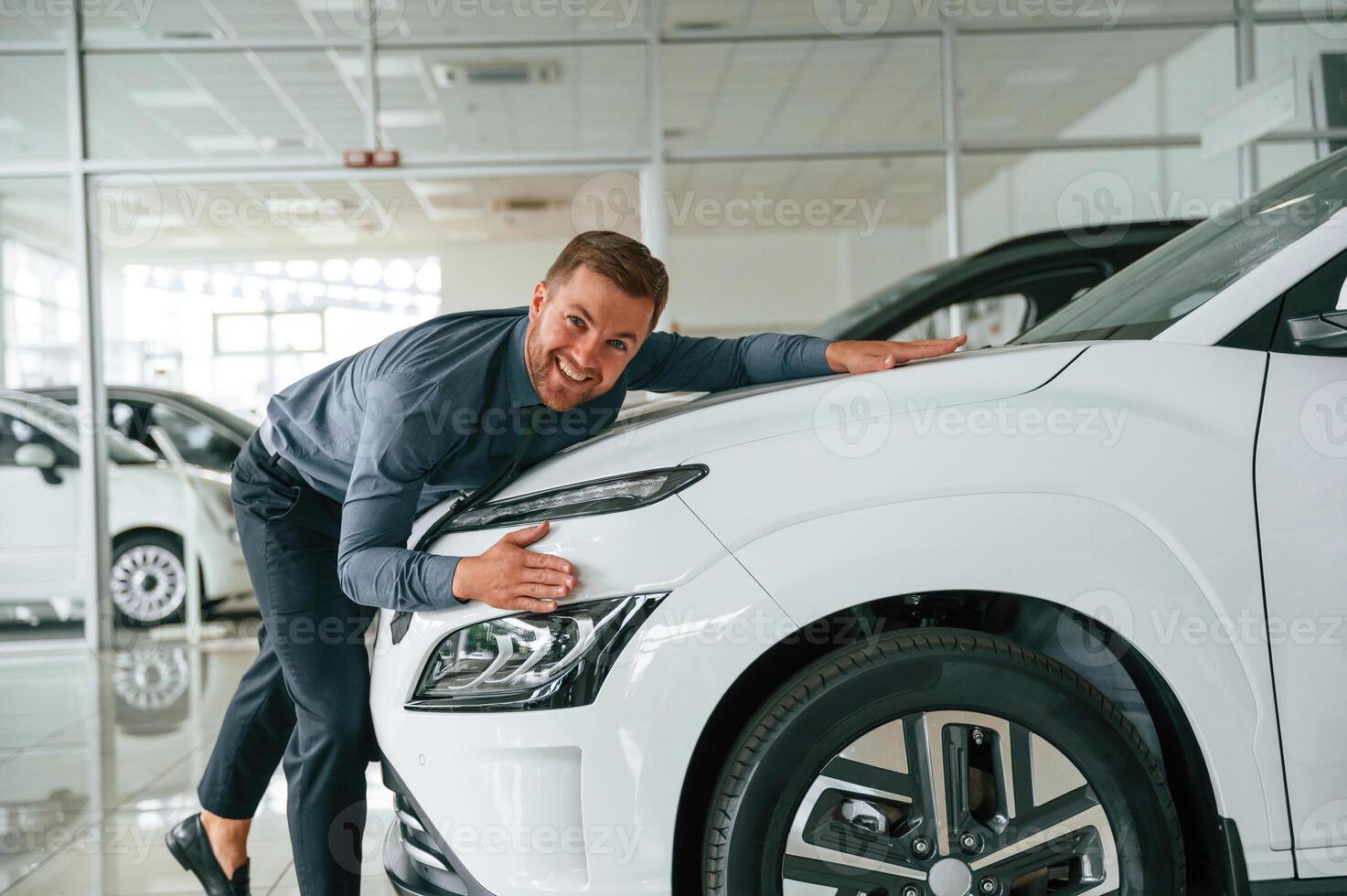 Embracing the new automobile.. Handsome car dealership worker is with electric vehicle photo