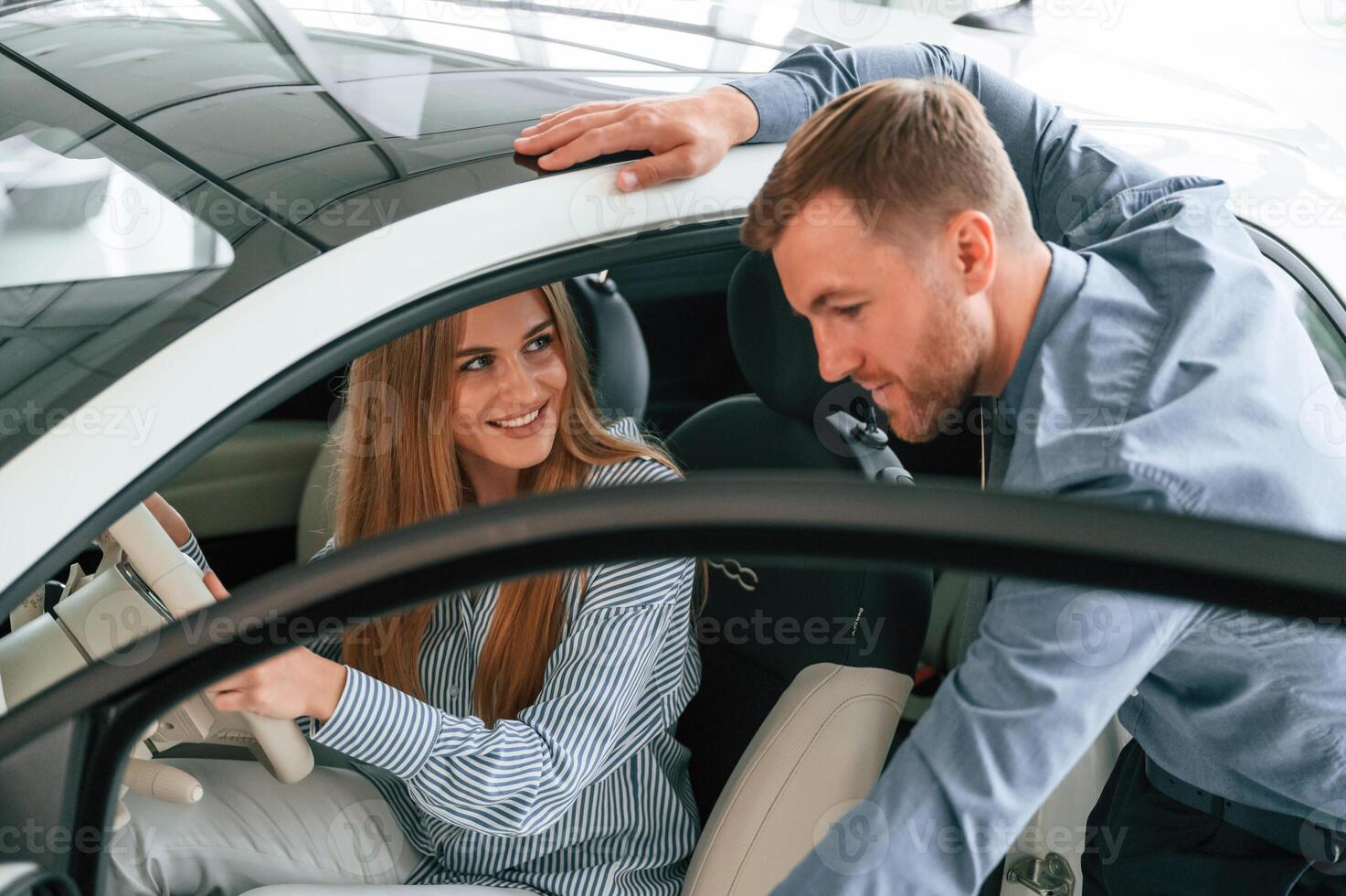 Explaining how, automobile, works. Man in formal clothes is with woman customer with the electric car photo