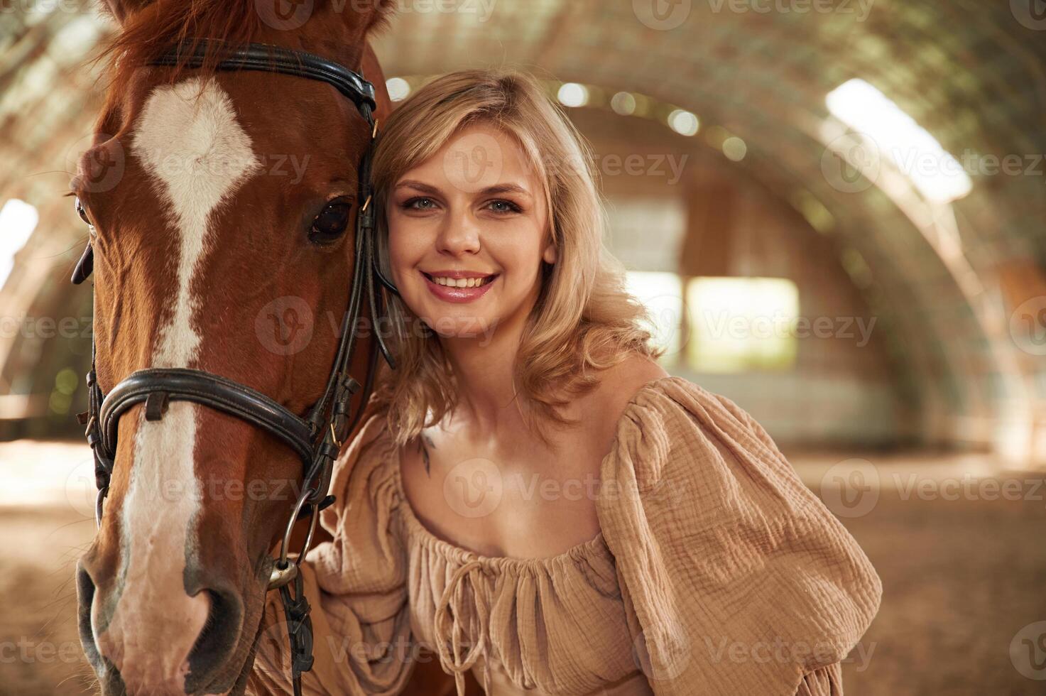 Portrait of beautiful young woman that is with horse indoors photo