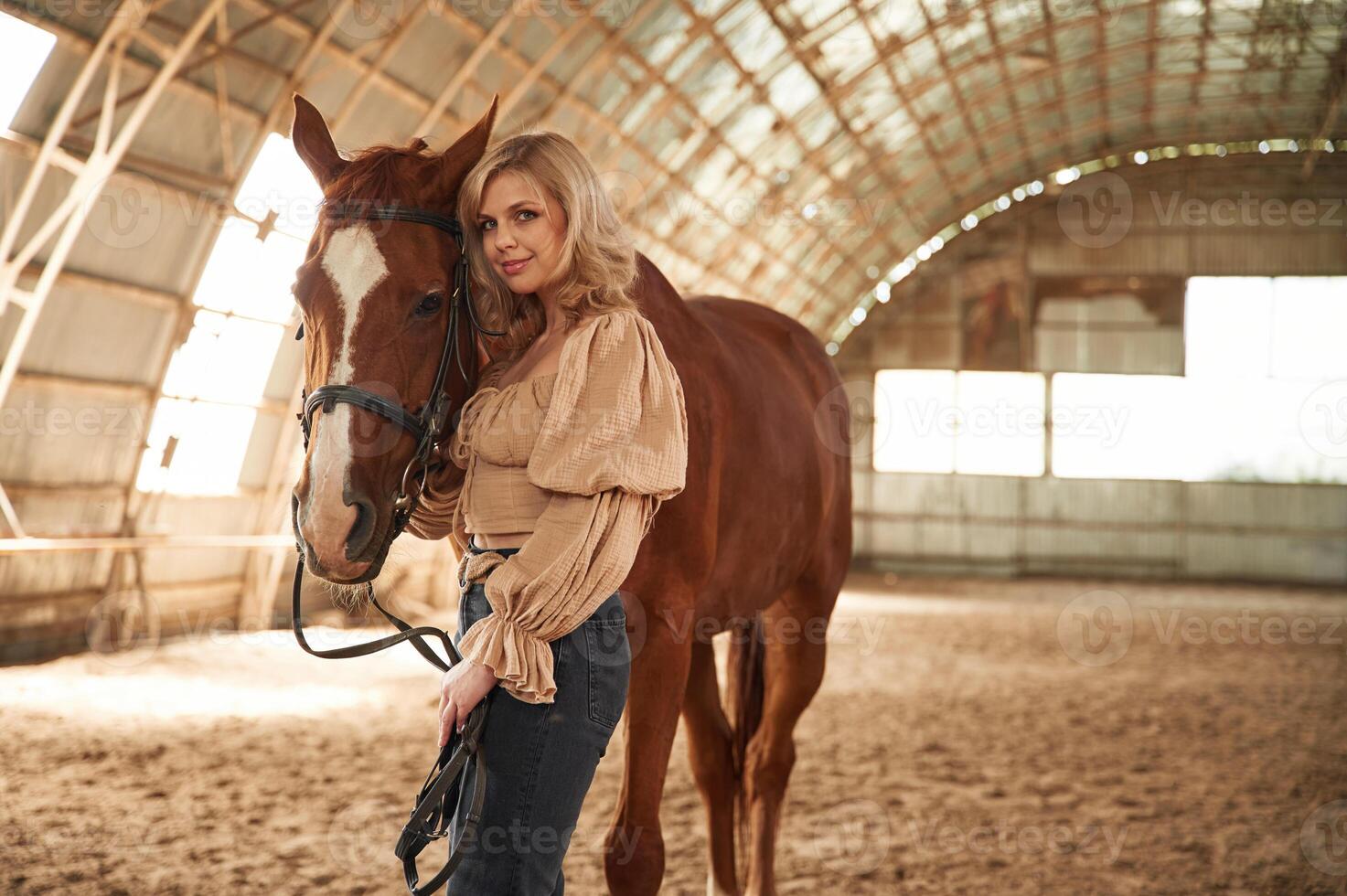 Sunny, day. Standing,with animal. Beautiful young woman is with horse indoors photo