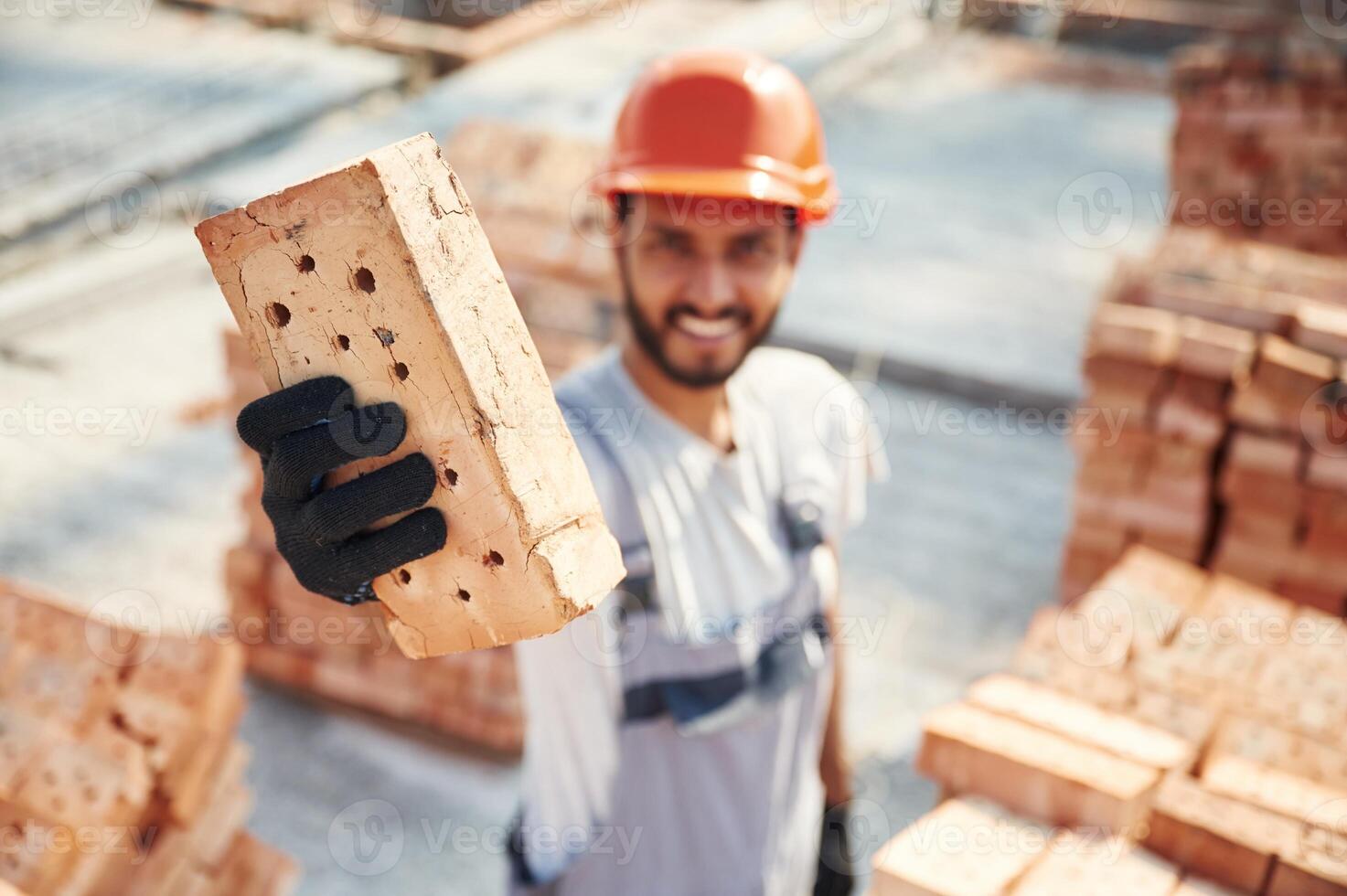 Close ,up, view ,of brick that ,is in the hands. Handsome Indian man is on the construction site photo