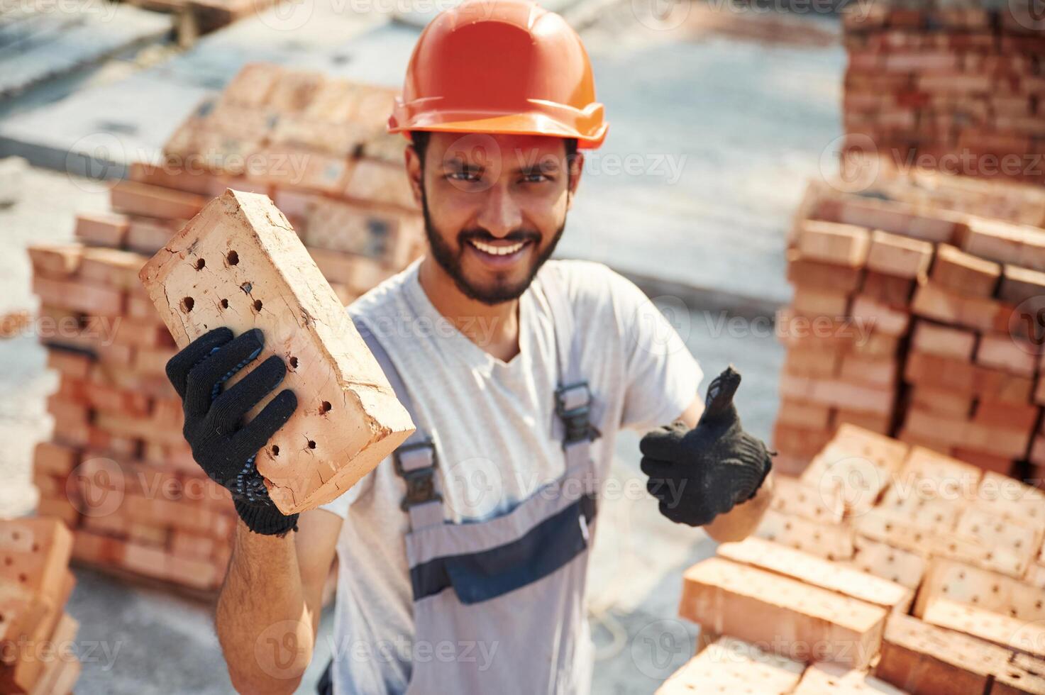 Close ,up, view ,of brick that is in the, hands. Handsome Indian man is on the construction site photo