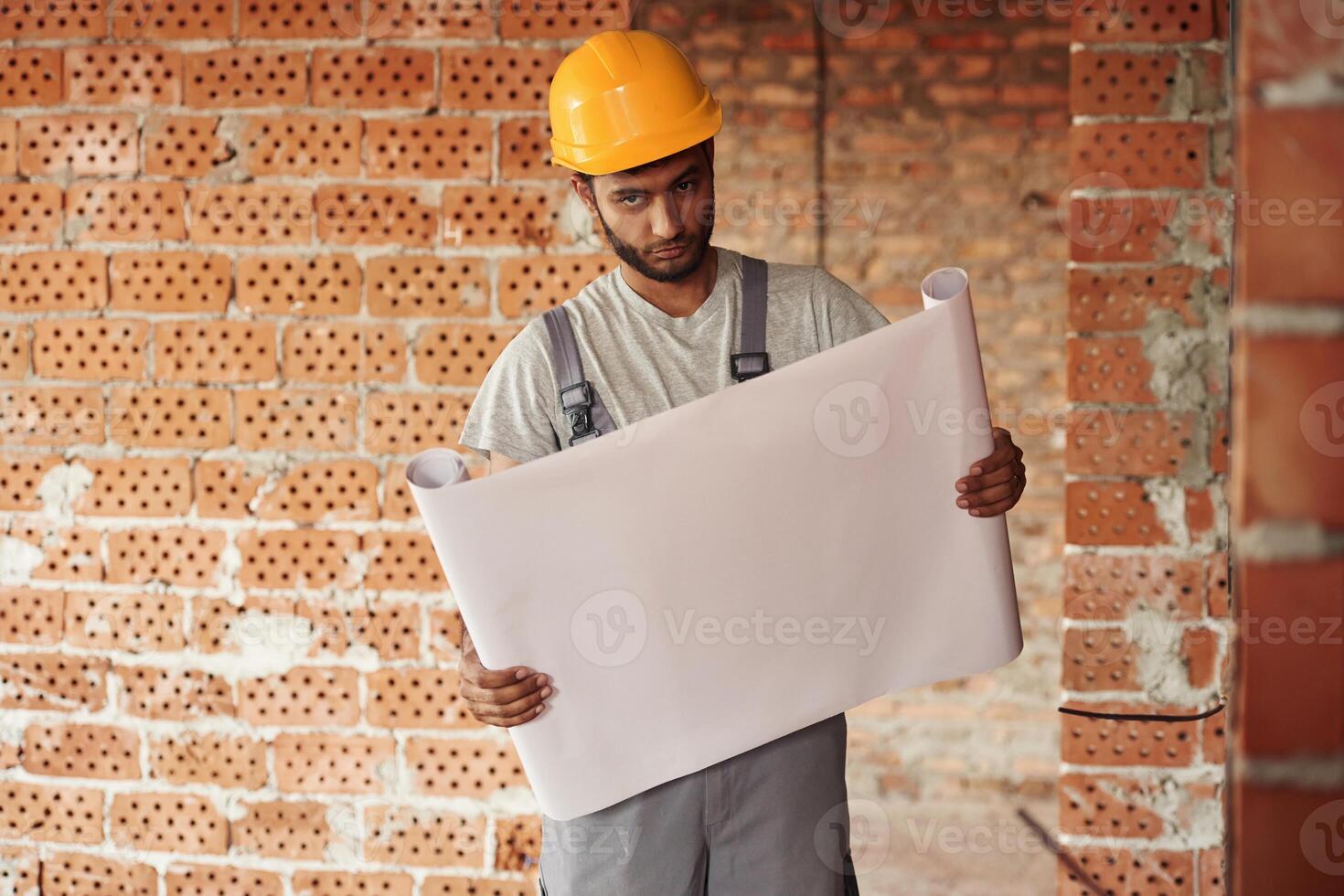 Holding the, document. Handsome Indian man is on the construction site photo