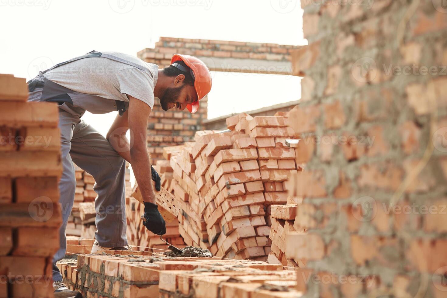 Bunch, of,, bricks. Placing them. Handsome Indian man is on the construction site photo