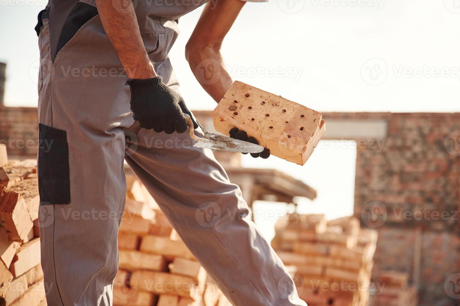 With, brick in hands. Close up view of man that is working on the construction site photo