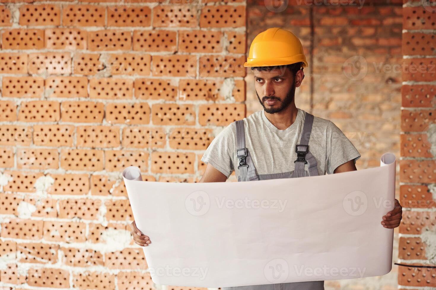 Holding the document. Handsome Indian man is on the construction site photo