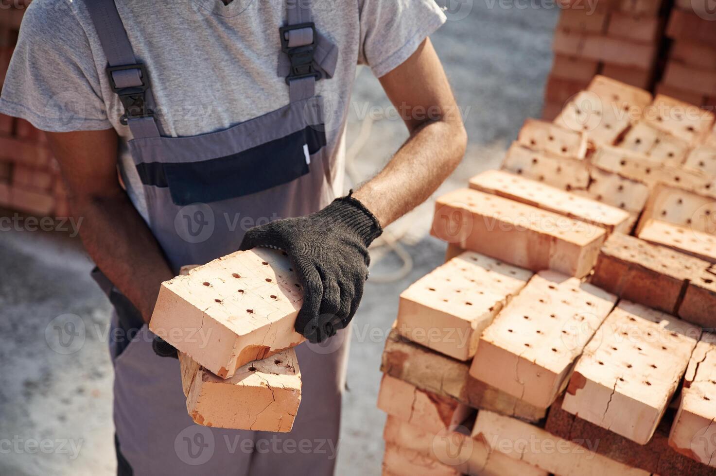 With brick in hands. .Close, up view of man that is working on the construction site photo