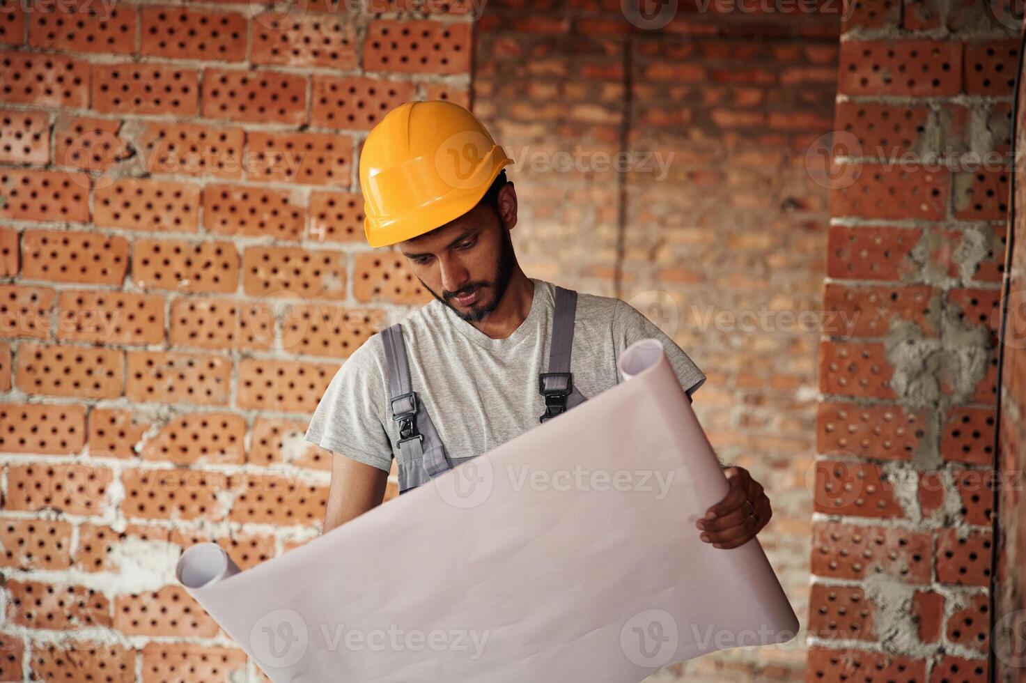Holding, the document.. Handsome Indian man is on the construction site photo