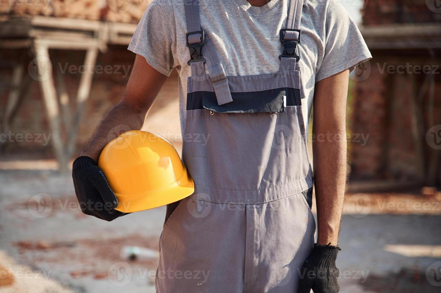 Holding yellow colored hard hat. Close up view of man that is working on the construction site photo