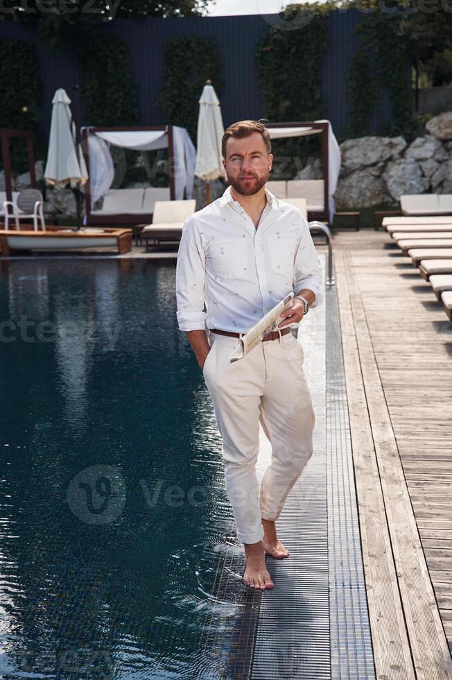 Business look, standing. Handsome man, in formal clothes is in the pool photo