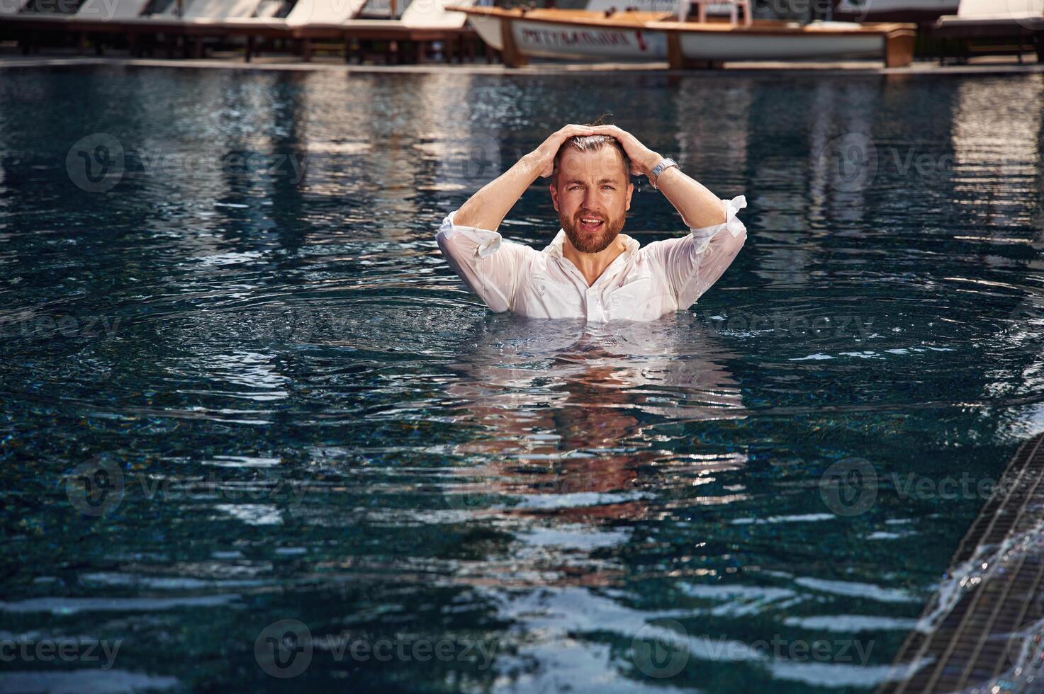 Handsome, man in formal clothes is in the pool photo