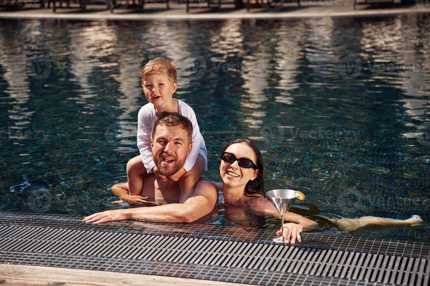 Front view. Happy family, of father, mother and son are in the pool photo