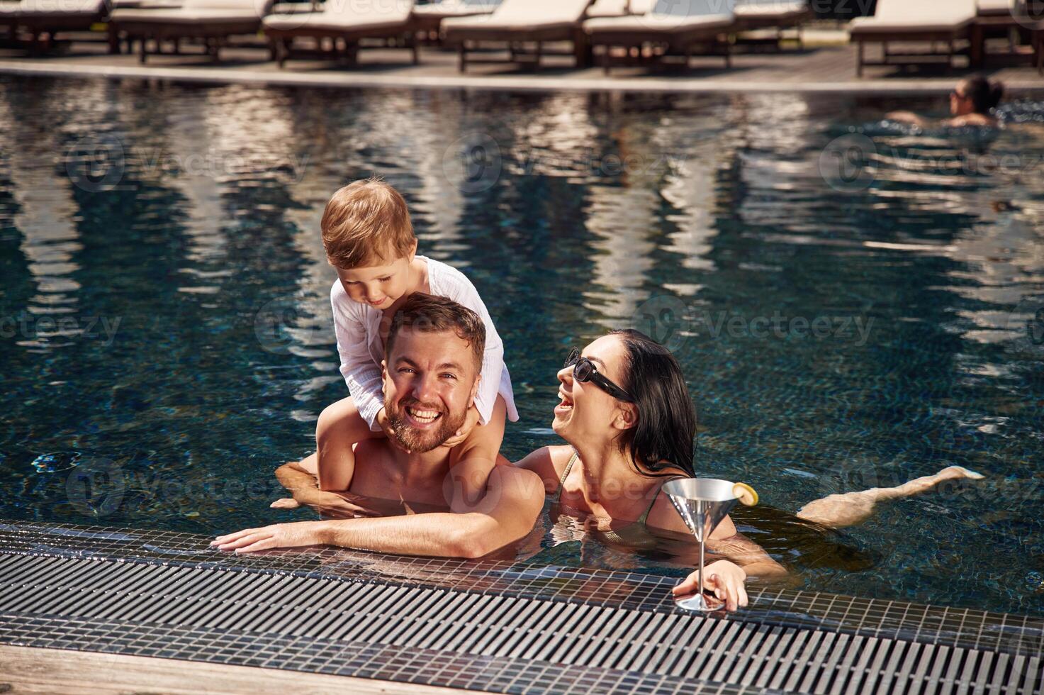 Front, view. Happy family ,of father, mother and son are in the pool photo