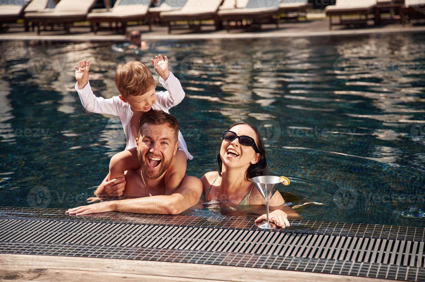 Front, view. Happy, family of, father, mother and son are in the pool photo