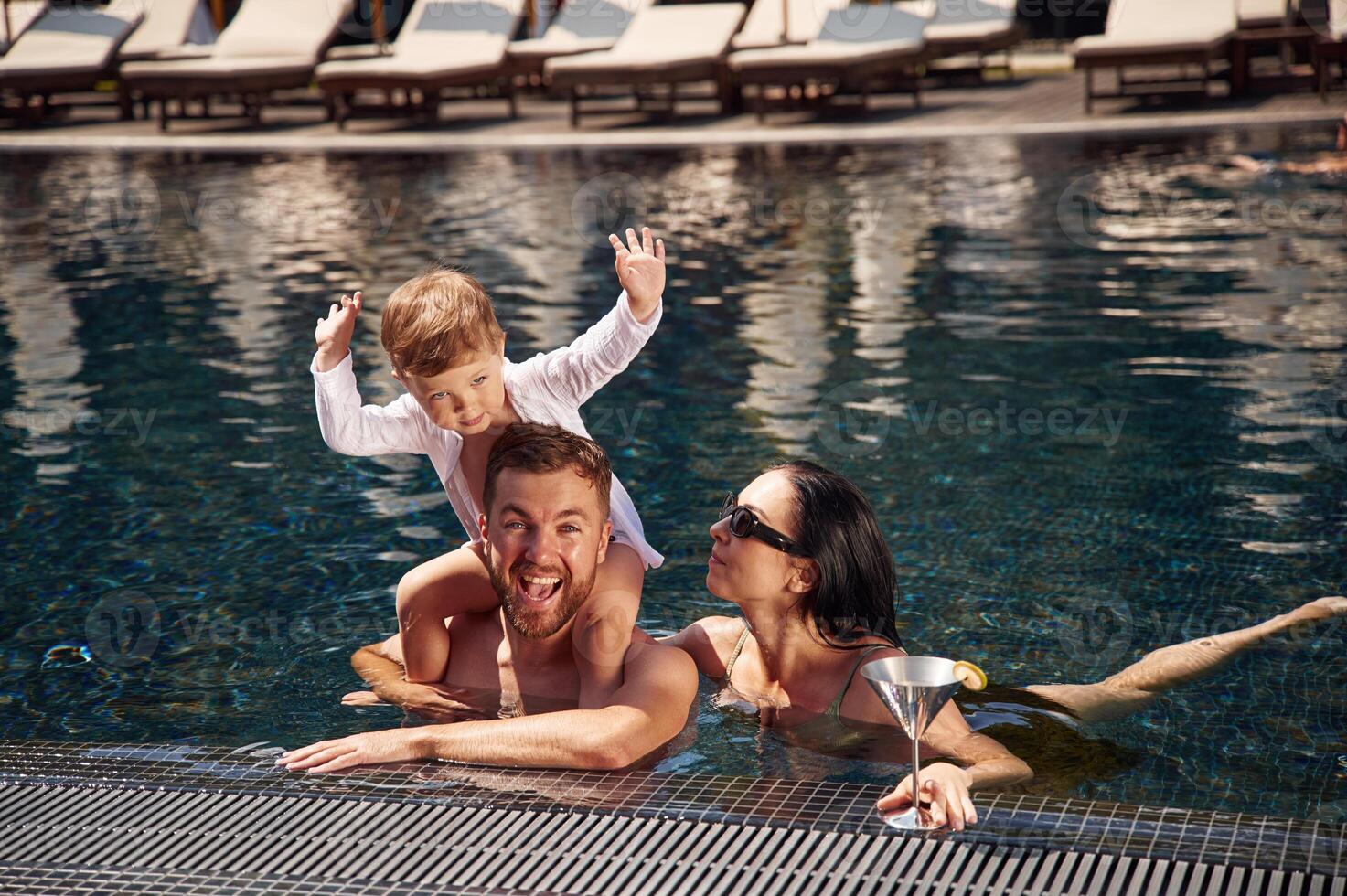 Front view. Happy family of, father, mother and son are in the pool photo