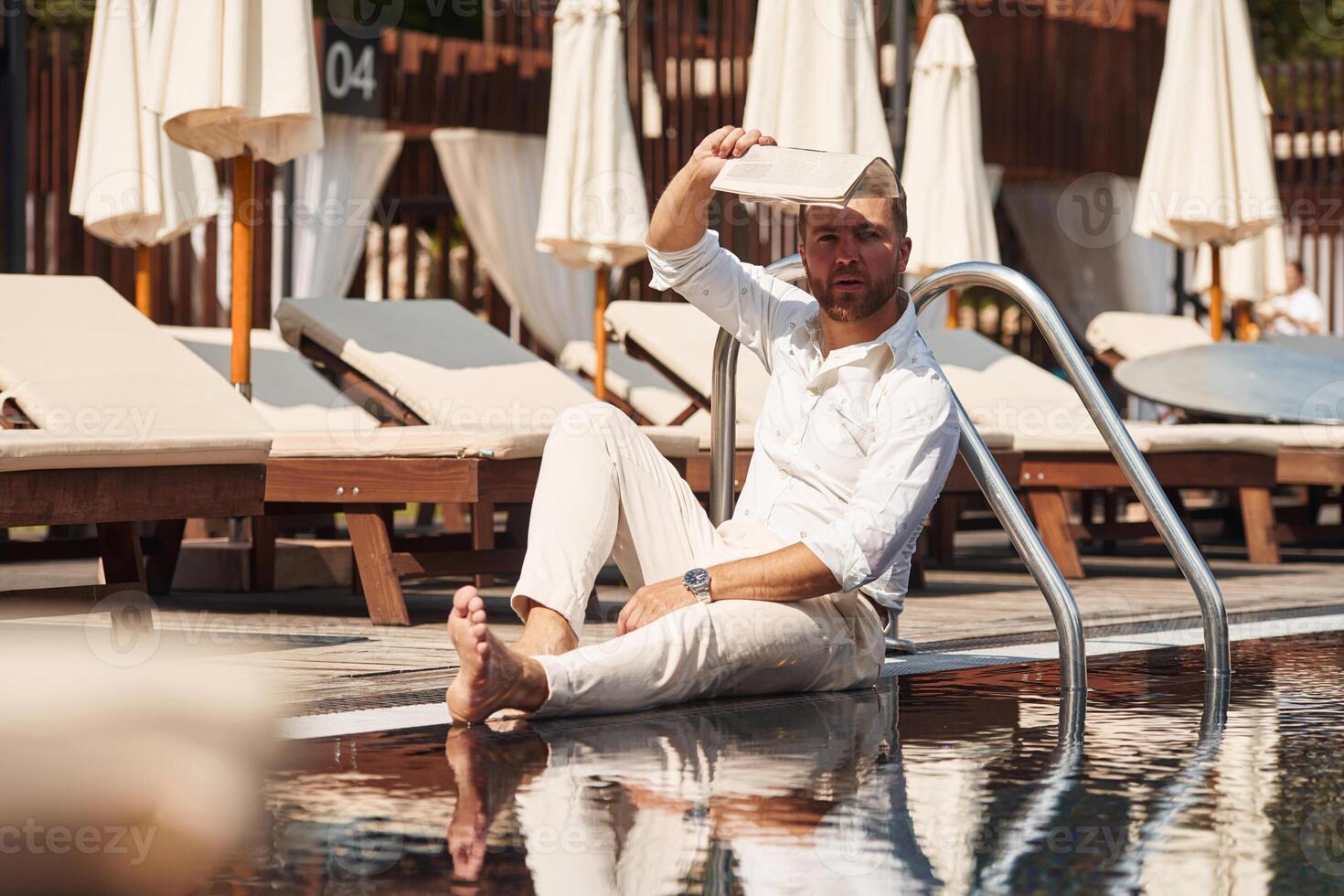 Sitting, taking a rest. Handsome man in formal clothes is in the pool photo