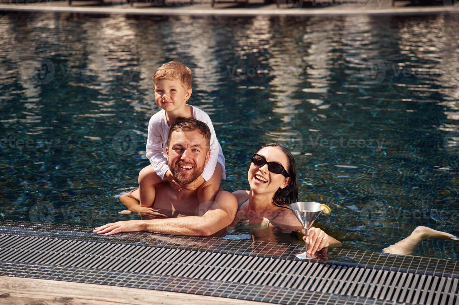 Front, view. Happy, family ,of father, mother and son are in the pool photo