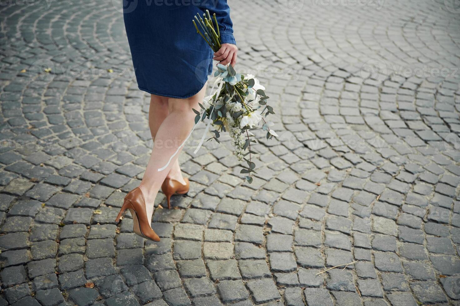 Legs, walking forward. Close up view of woman that is with flowers in hands photo