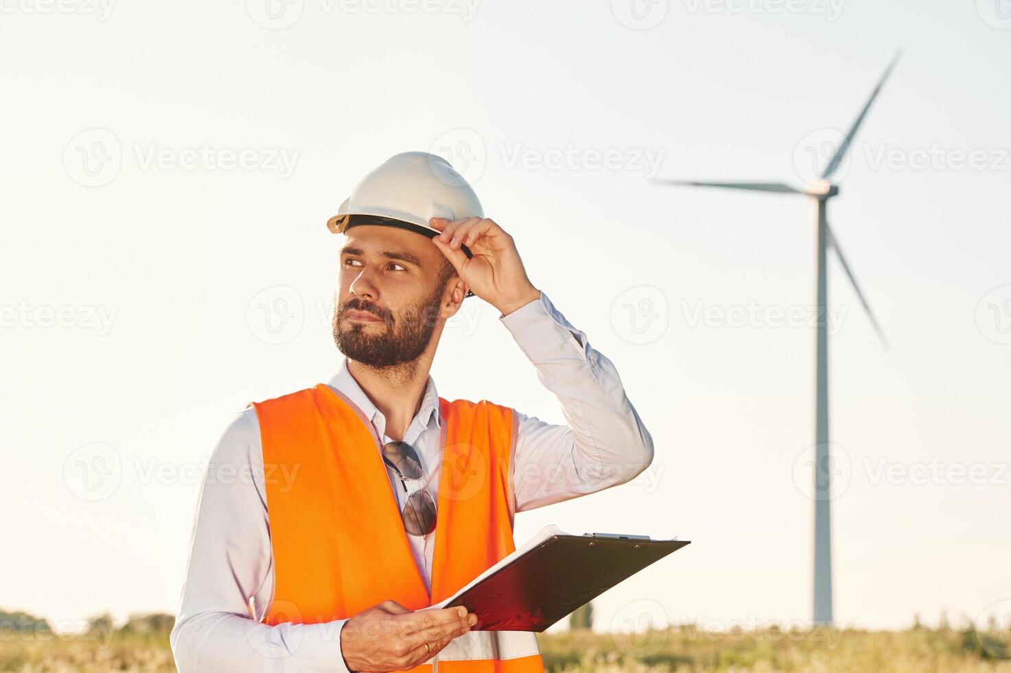 With notepad. Service engineer is on ,the field with windmills photo