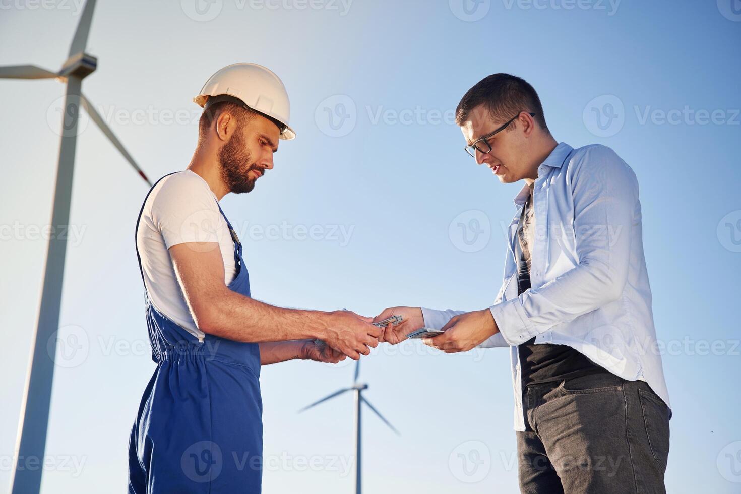 Making dea,l with businessman. Service engineer is on the field with windmills photo