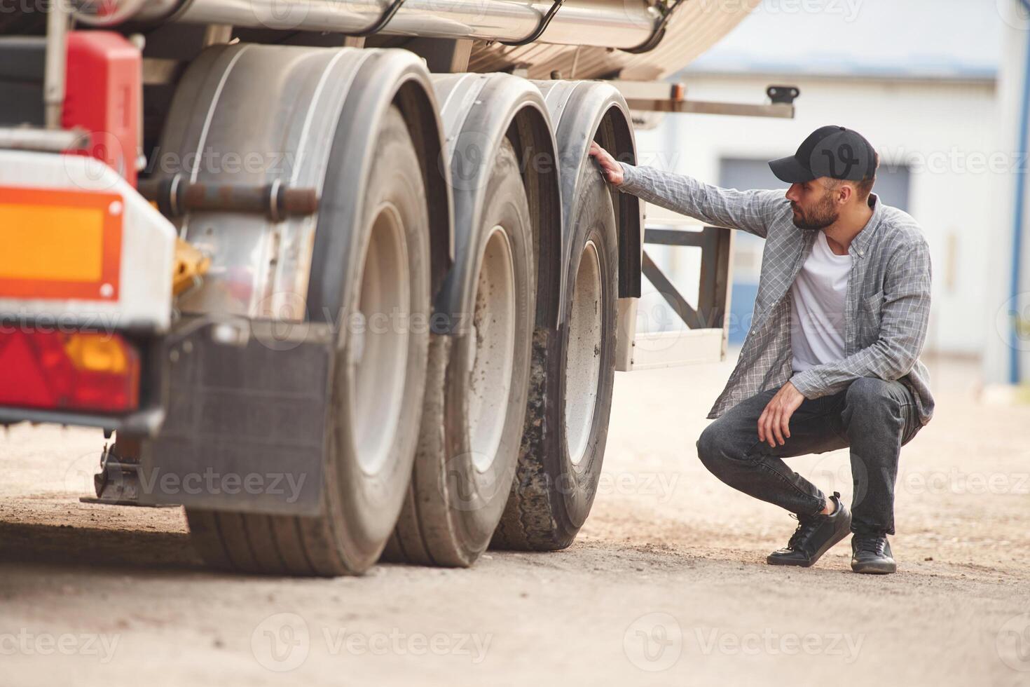 Checking the wheels. Young truck ,drive,r in casual clothes photo