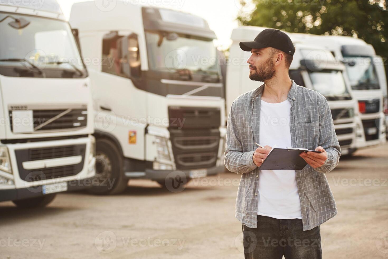 Notepad, in hands. Young truck, driver in casual clothes photo
