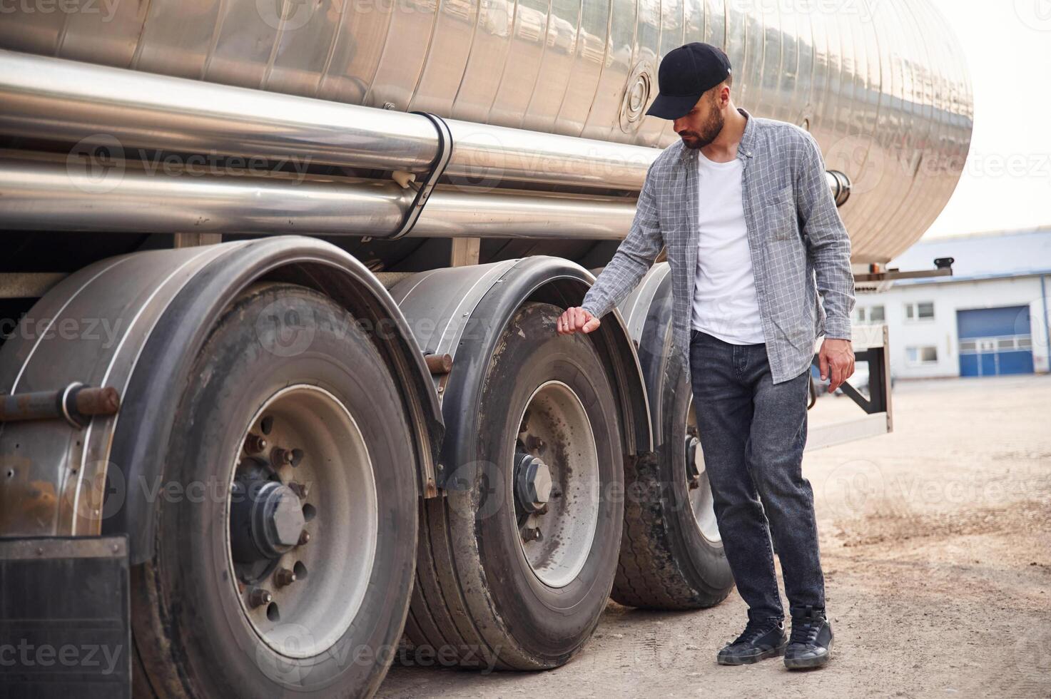 Checking, the wheels,. Young truck driver in casual clothes photo