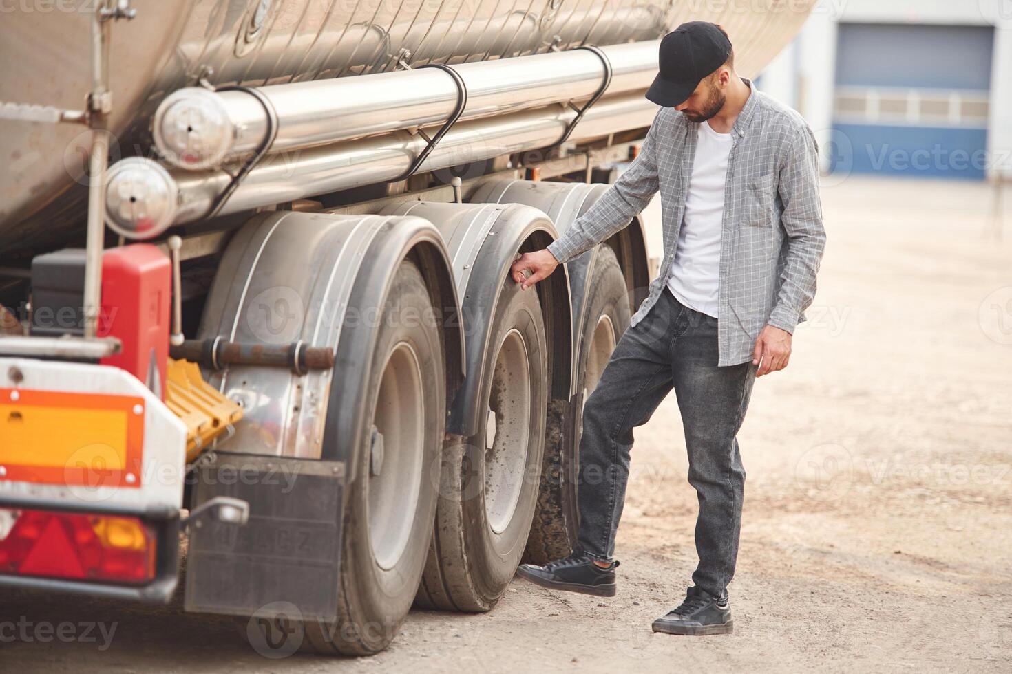 Checking the wheels. Young truck, driver in casual clothes photo
