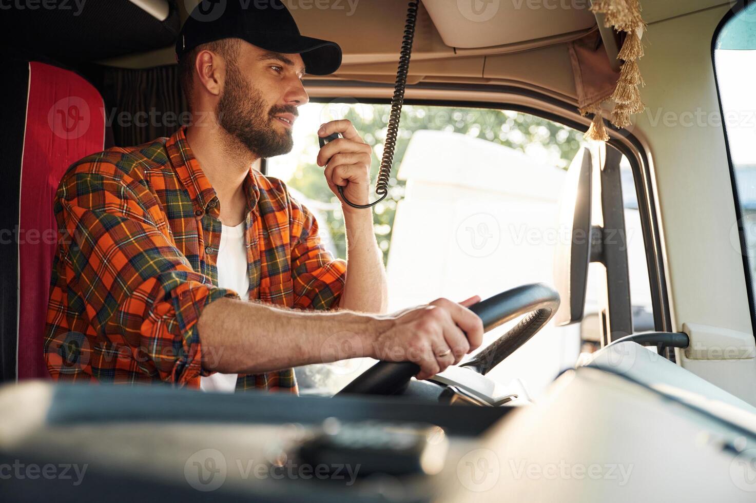 Communication by using radio. Young truck driver in casual clothes photo
