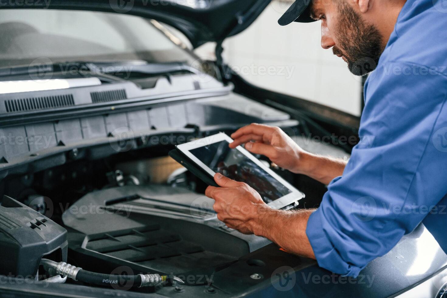 With, tablet in hands.. Auto ,mechanic working in garage. Repair service photo