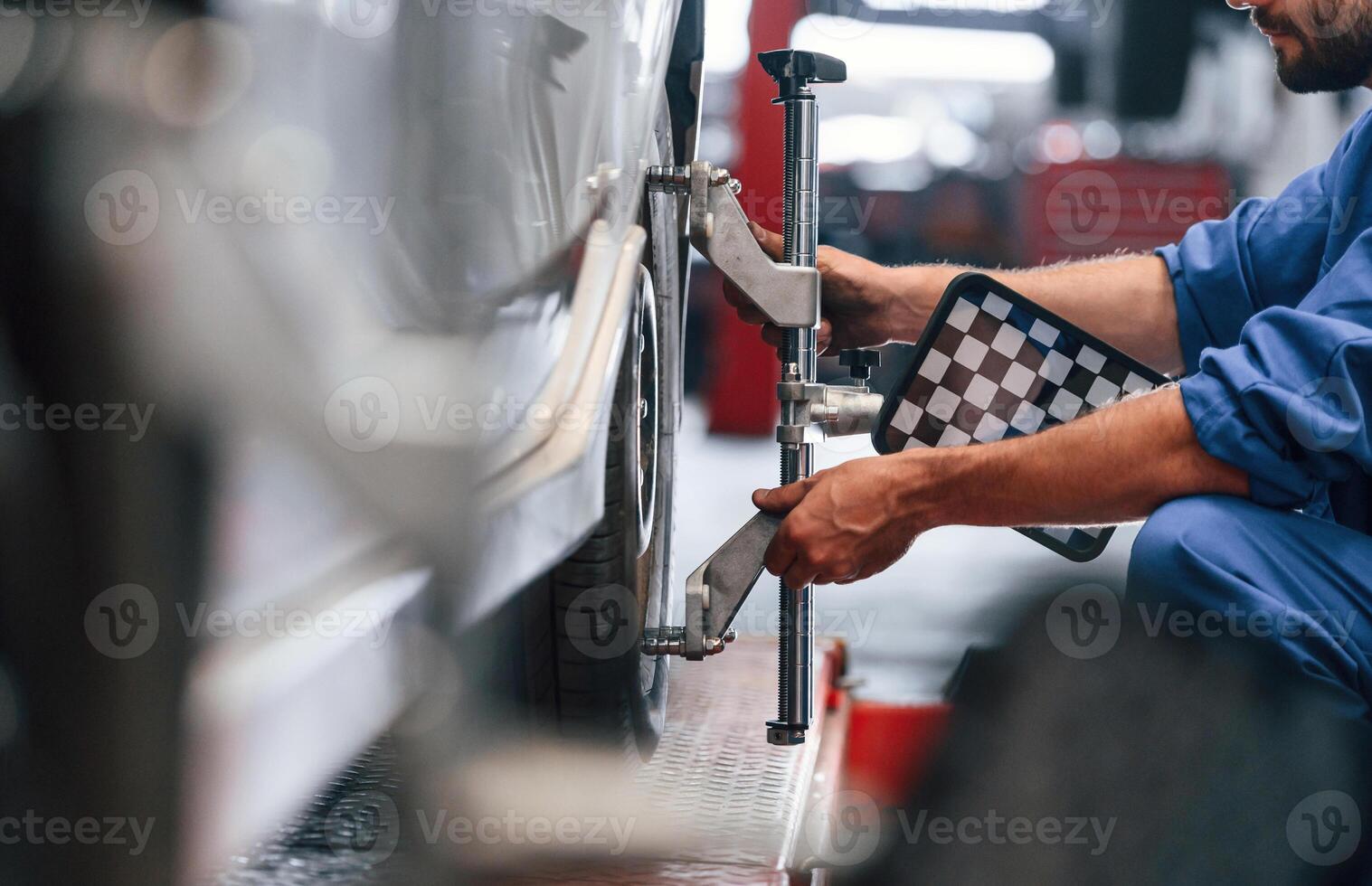 Sitting, checking ,the, tire. Auto mechanic working in garage. Repair service photo