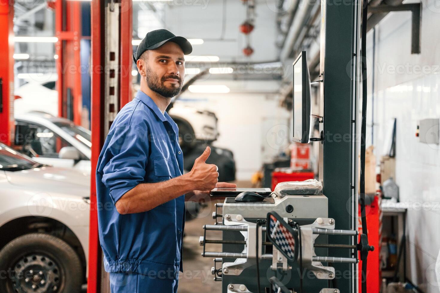 Standing by computer terminal,. Auto ,mechanic working in garage. Repair service photo