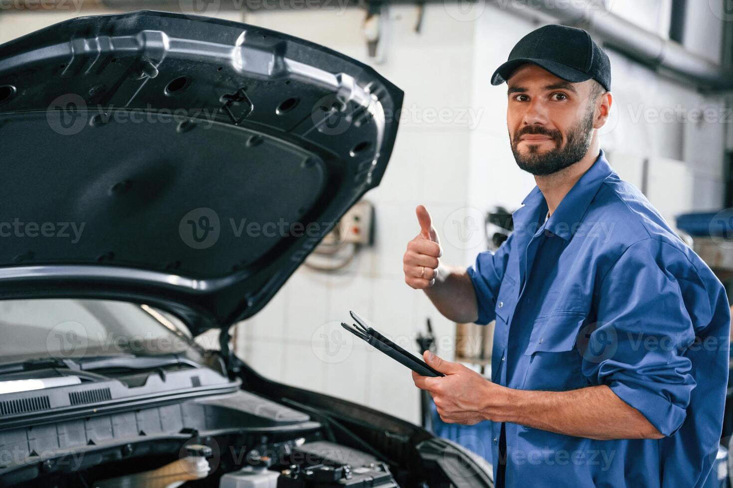 With ,tablet in hands.. Auto mechanic working in garage. Repair service photo