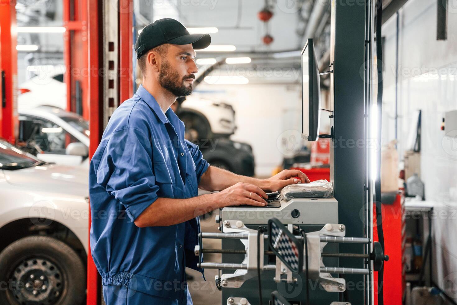 Standing by computer ,terminal. Auto mechanic working in garage. Repair service photo
