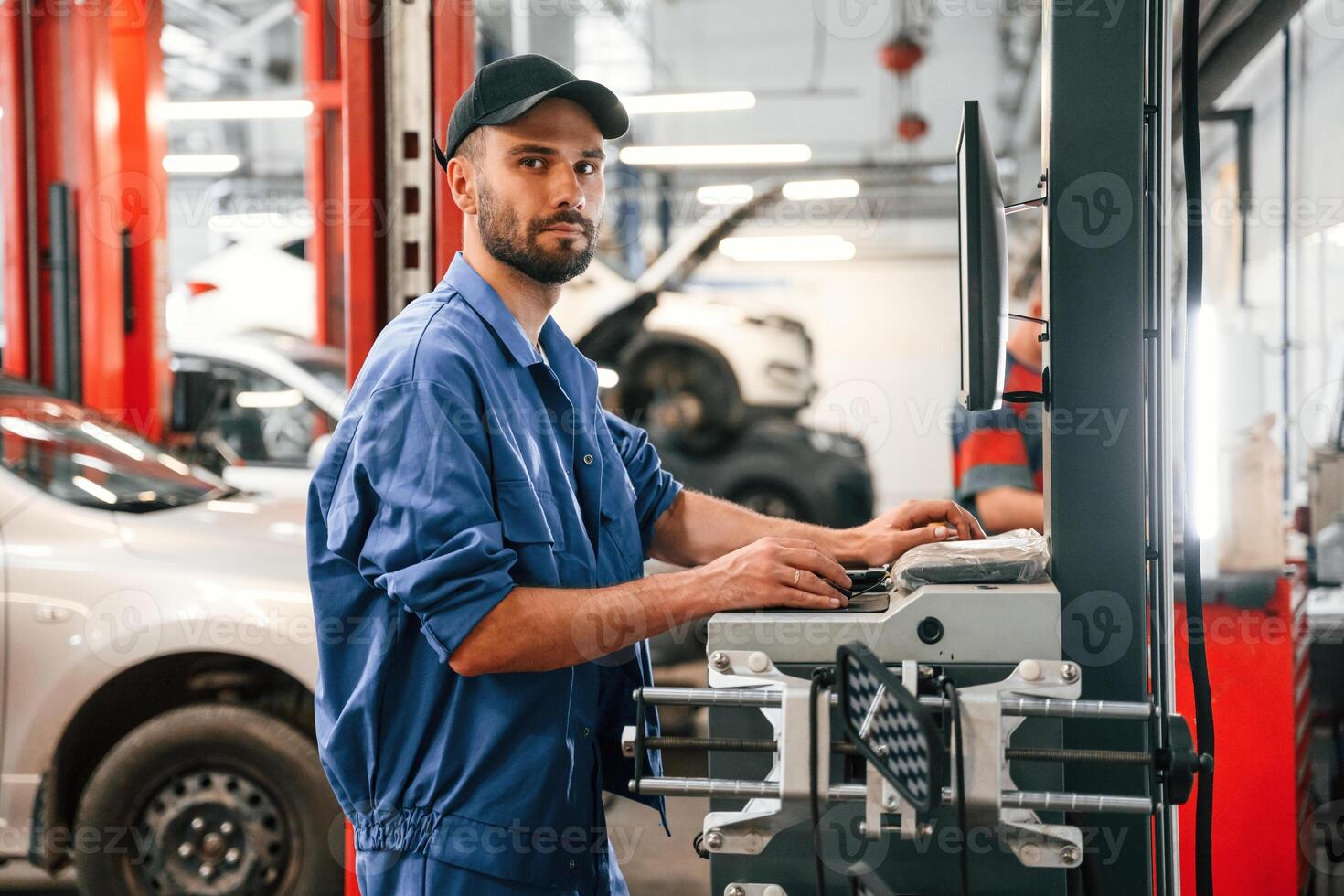 Side view, using computer. Auto mechanic working in garage. Repair service photo