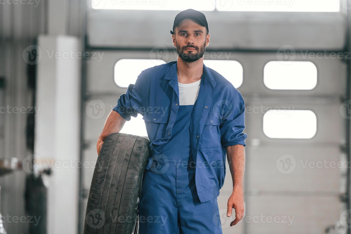 Tire ,in, hand. Auto mechanic working in garage. Repair service photo