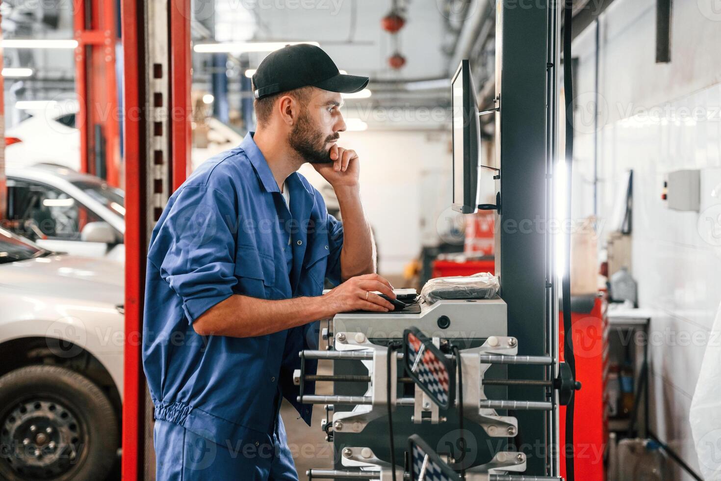 Standing by, computer terminal. Auto mechanic working in garage. Repair service photo