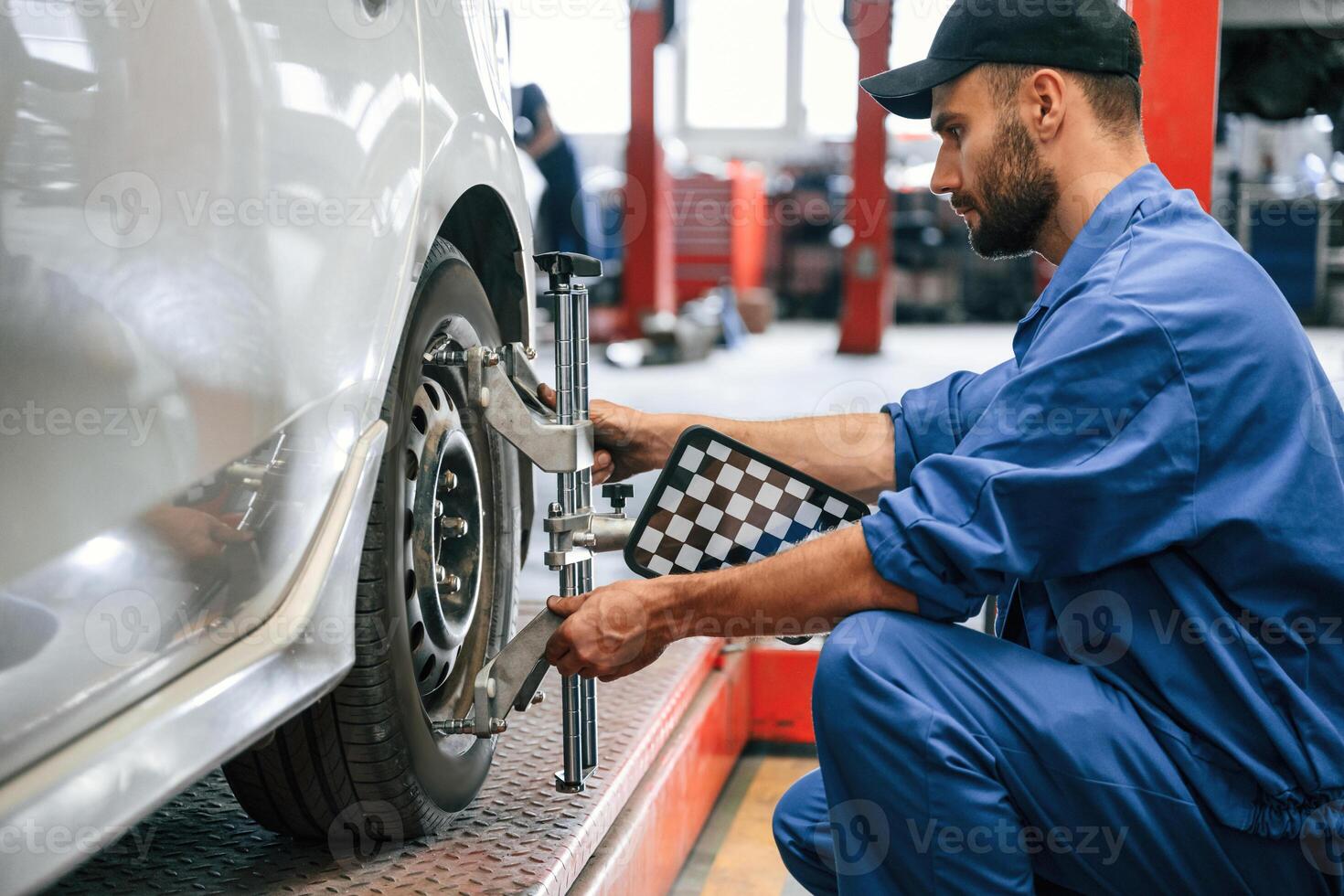 Taking care of wheel disk. Auto mechanic working in garage. Repair service photo