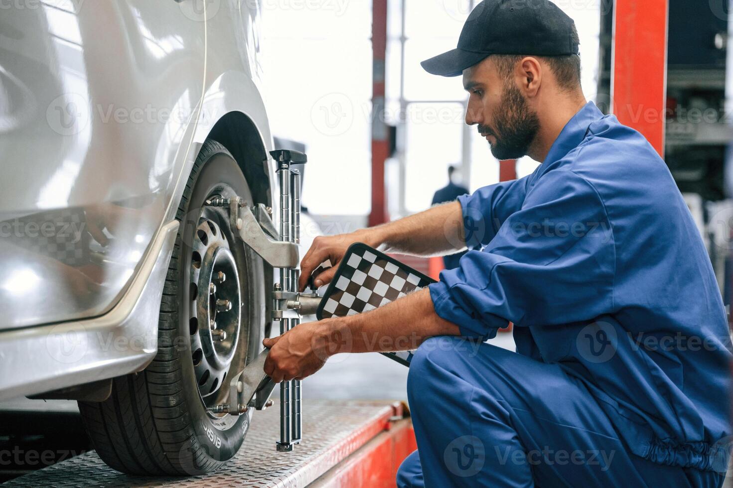 Taking care of wheel, disk. Auto mechanic working in garage. Repair service photo