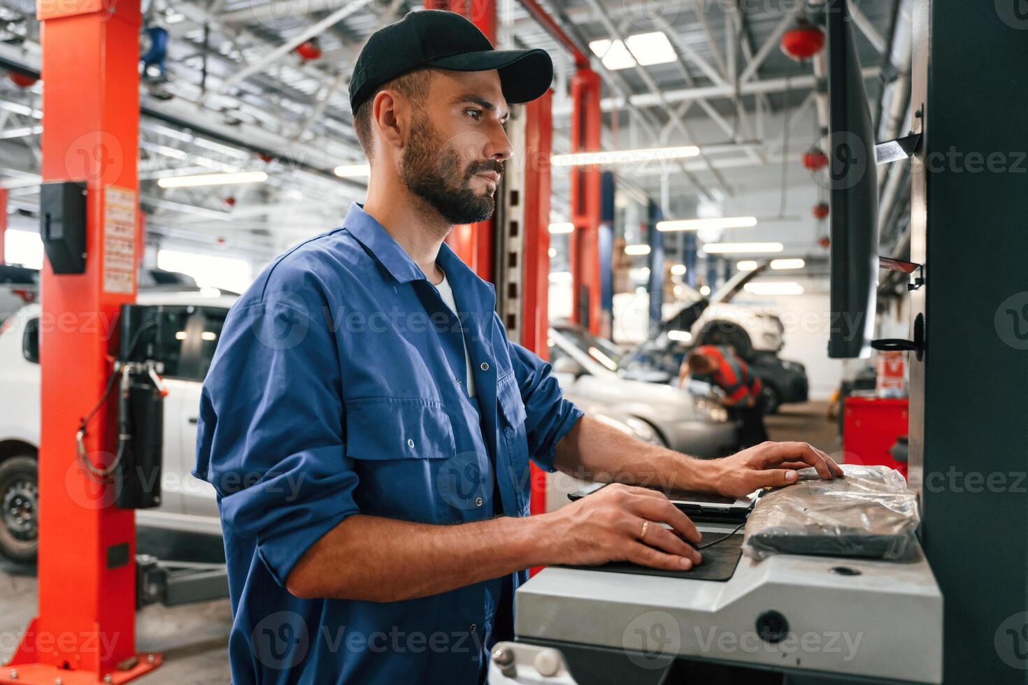 Side, view, using computer. Auto mechanic working in garage. Repair service photo