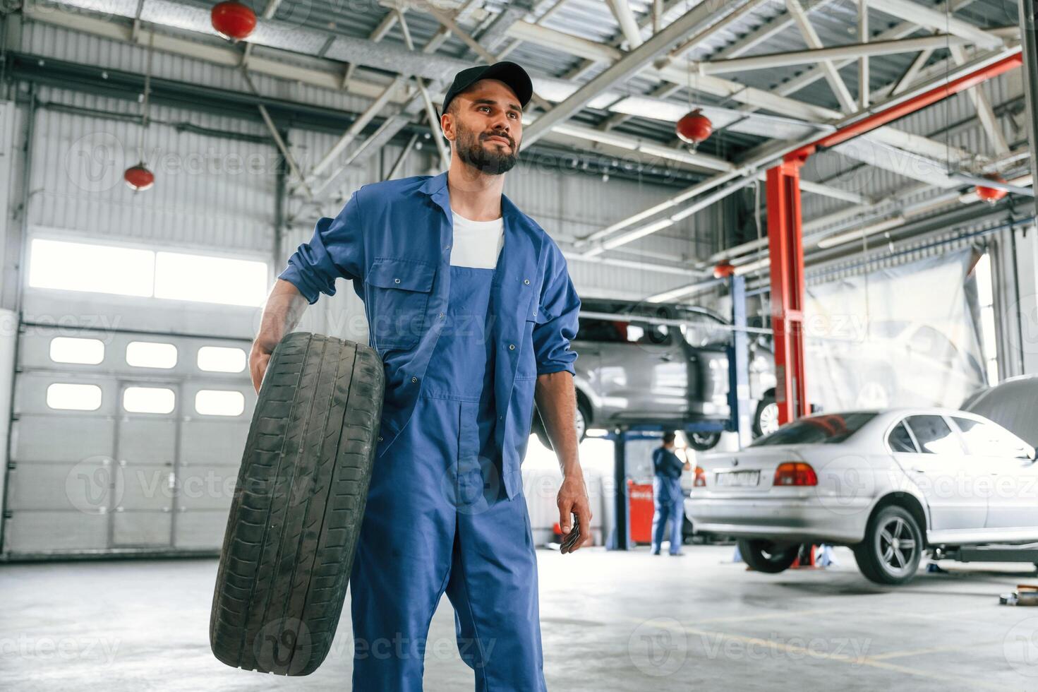 Walking, forward, with new tire. Auto mechanic working in garage. Repair service photo