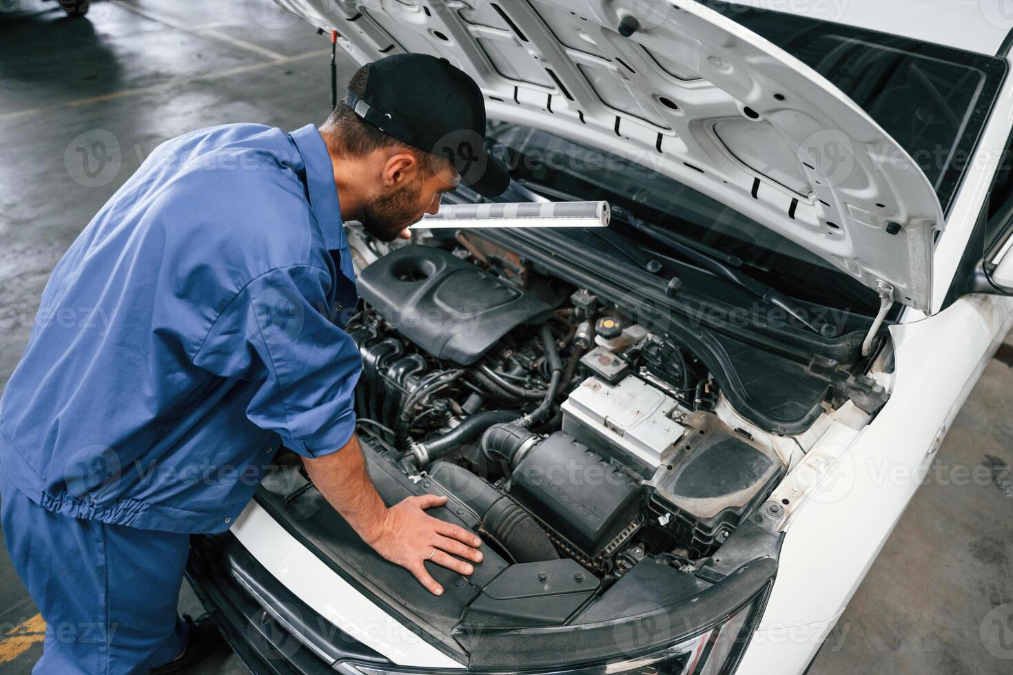 Top, view. Hood is opened. Auto mechanic working in garage. Repair service photo