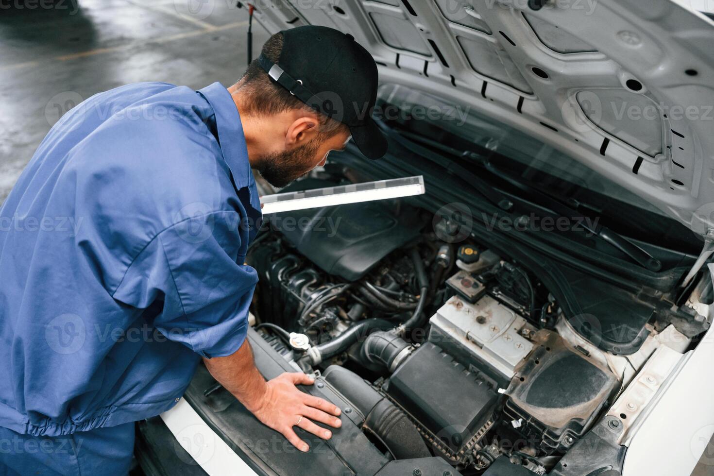 Top view. Hood ,is opened. Auto mechanic working in garage. Repair service photo